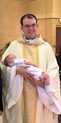 Fr Ponisciak, CSC with a newly baptized infant
