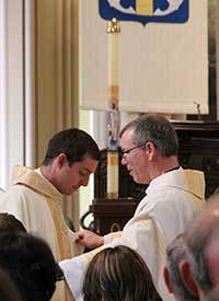 Fr Tom Looney, CSC helps Fr Chase Pepper, CSC with his vestments